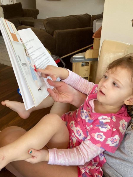 Little girl reading Brindy and the Red Rubber Boots book.